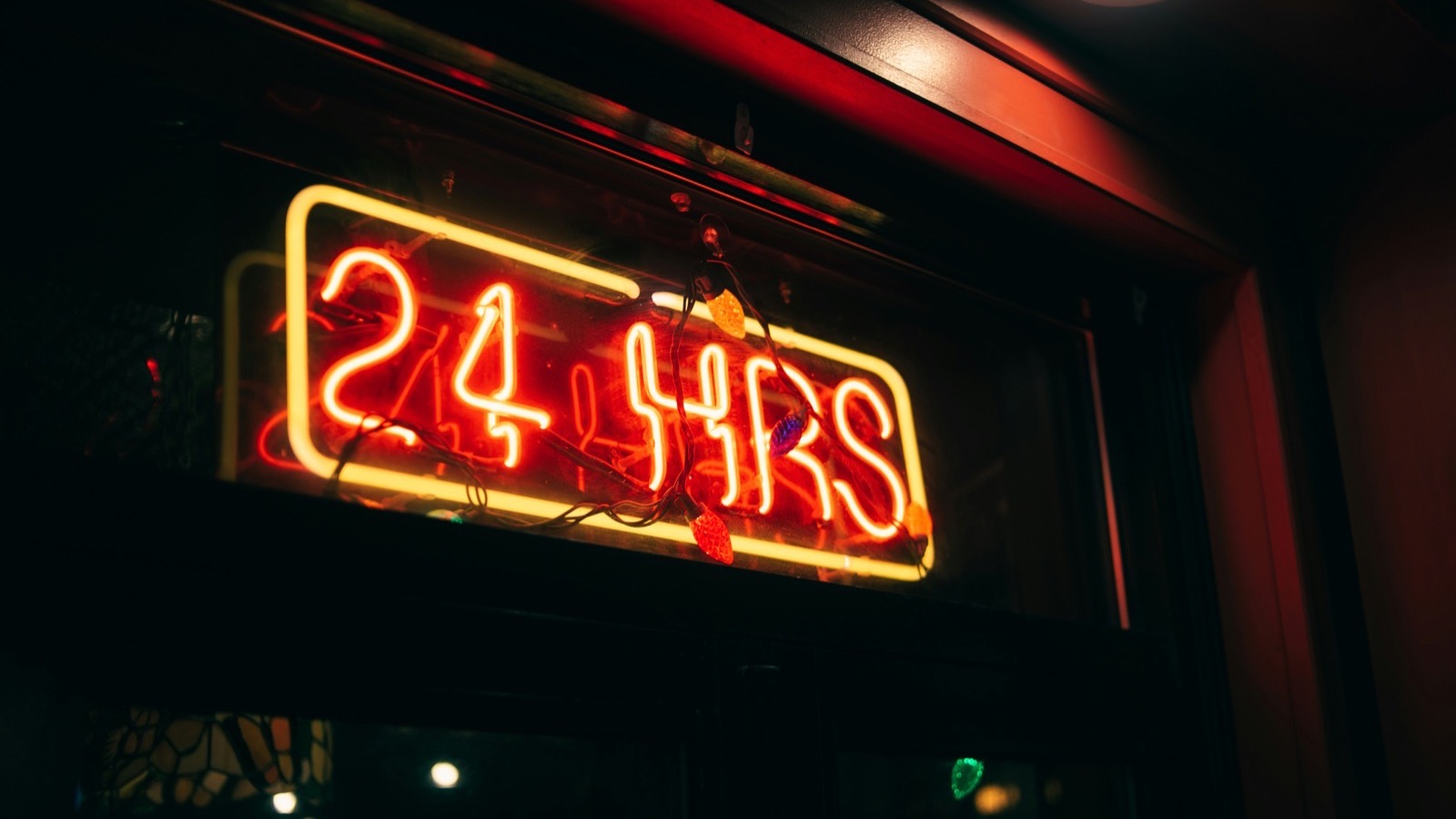 Neon sign reading 24 HRS above a doorway at night, a reminder of the NIS2 early-warning deadline
